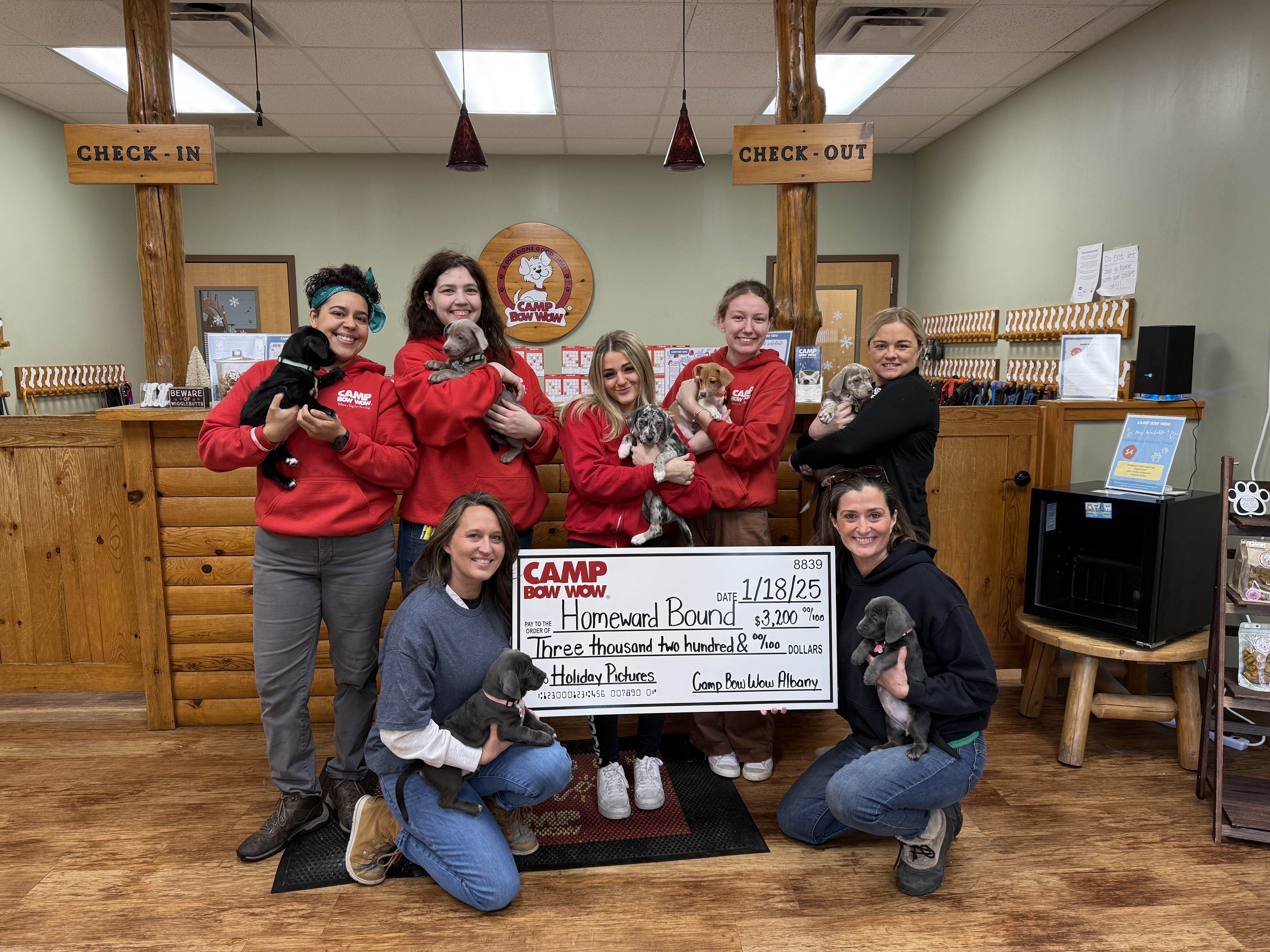 Camp Bow Wow Albany group photo holding a check and puppies